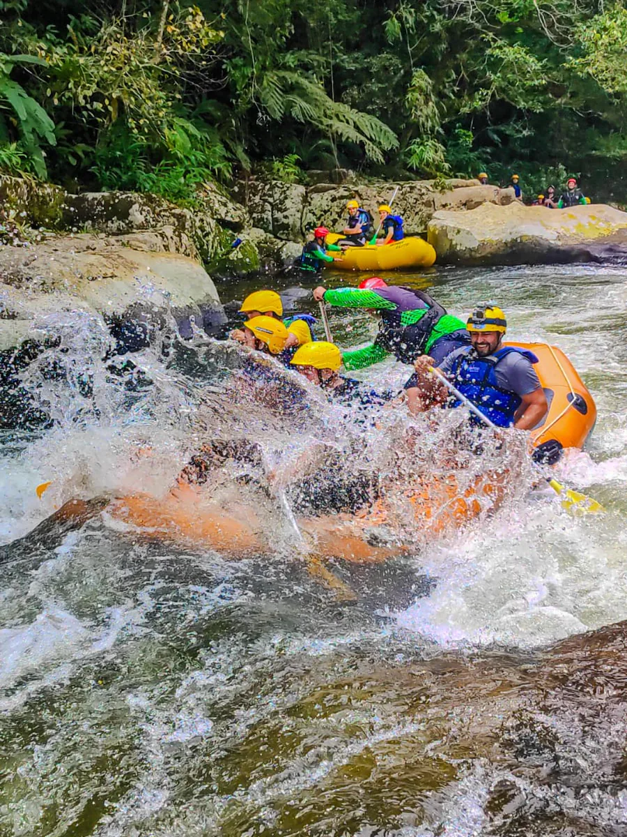 Dois botes descendo o rio entre pedras e mata fechada, com o guia dentro da embarcação