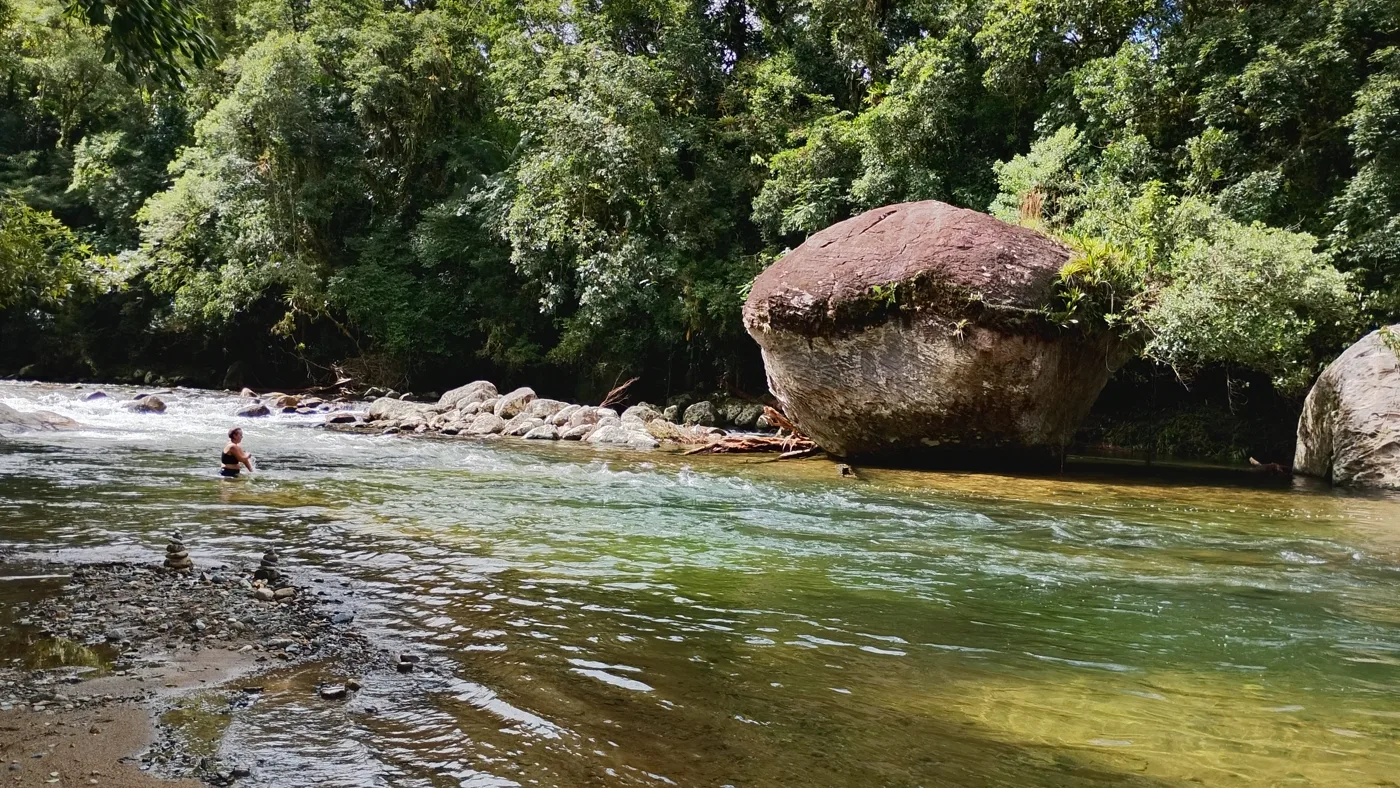 Pedregulho arredondado do tamanho de uma casa parado no meio do rio Cachoeira, com uma pessoa na água rasa
